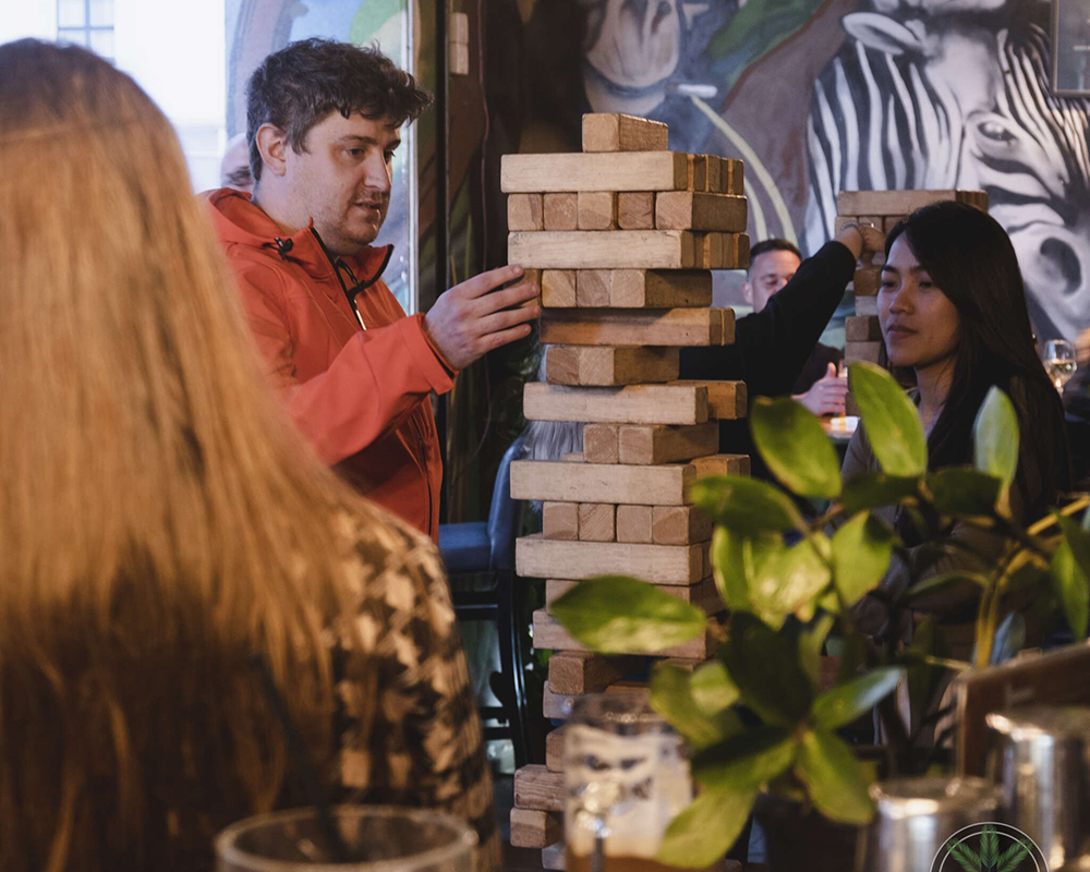 Enjoying Jenga Game in Jungle Joy's Outdoor Oasis, Framed by a Stunning Artistic Mural